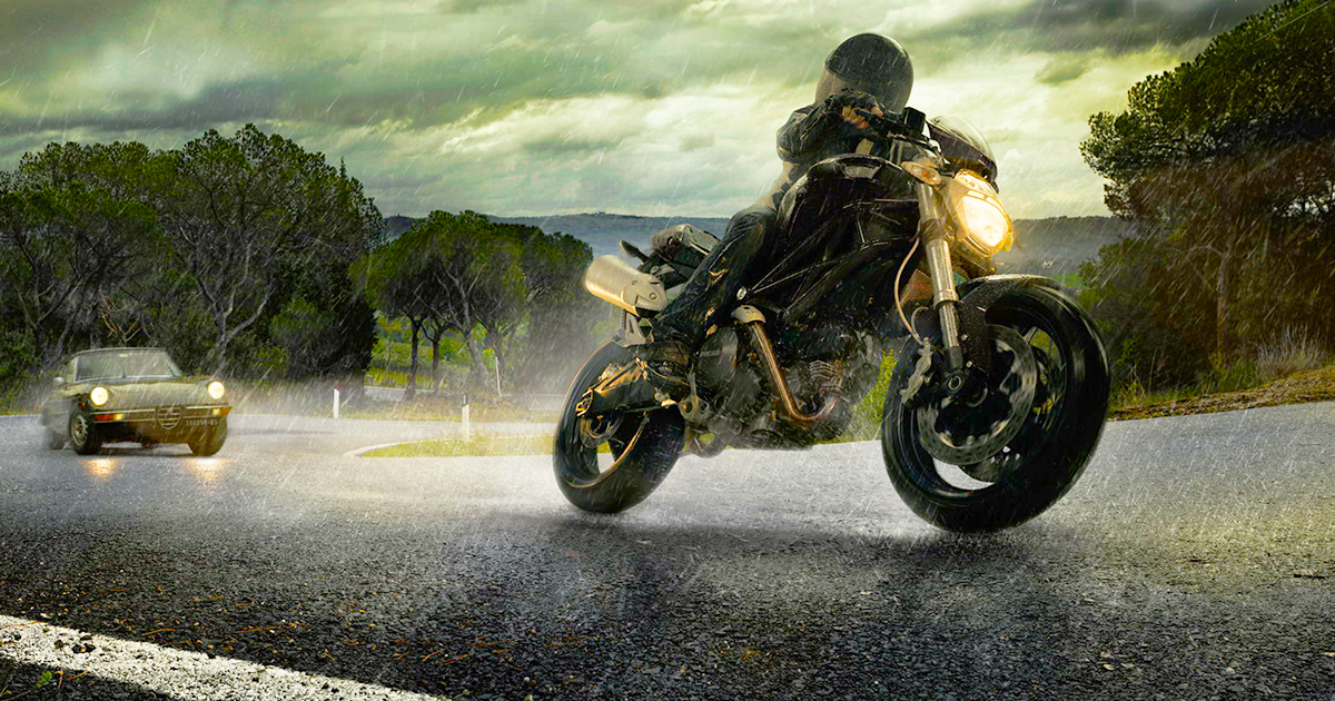 Motorkár jazdí po ceste na motorke v daždi