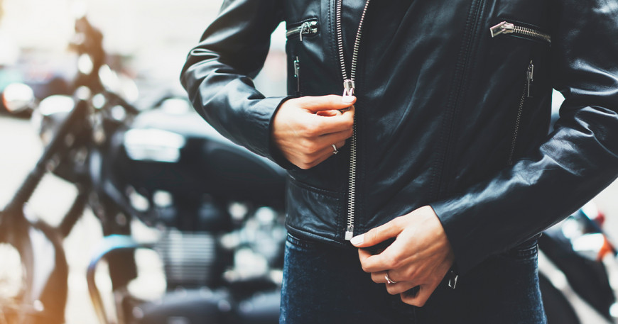 Muž si zapína koženú bundu na motorku