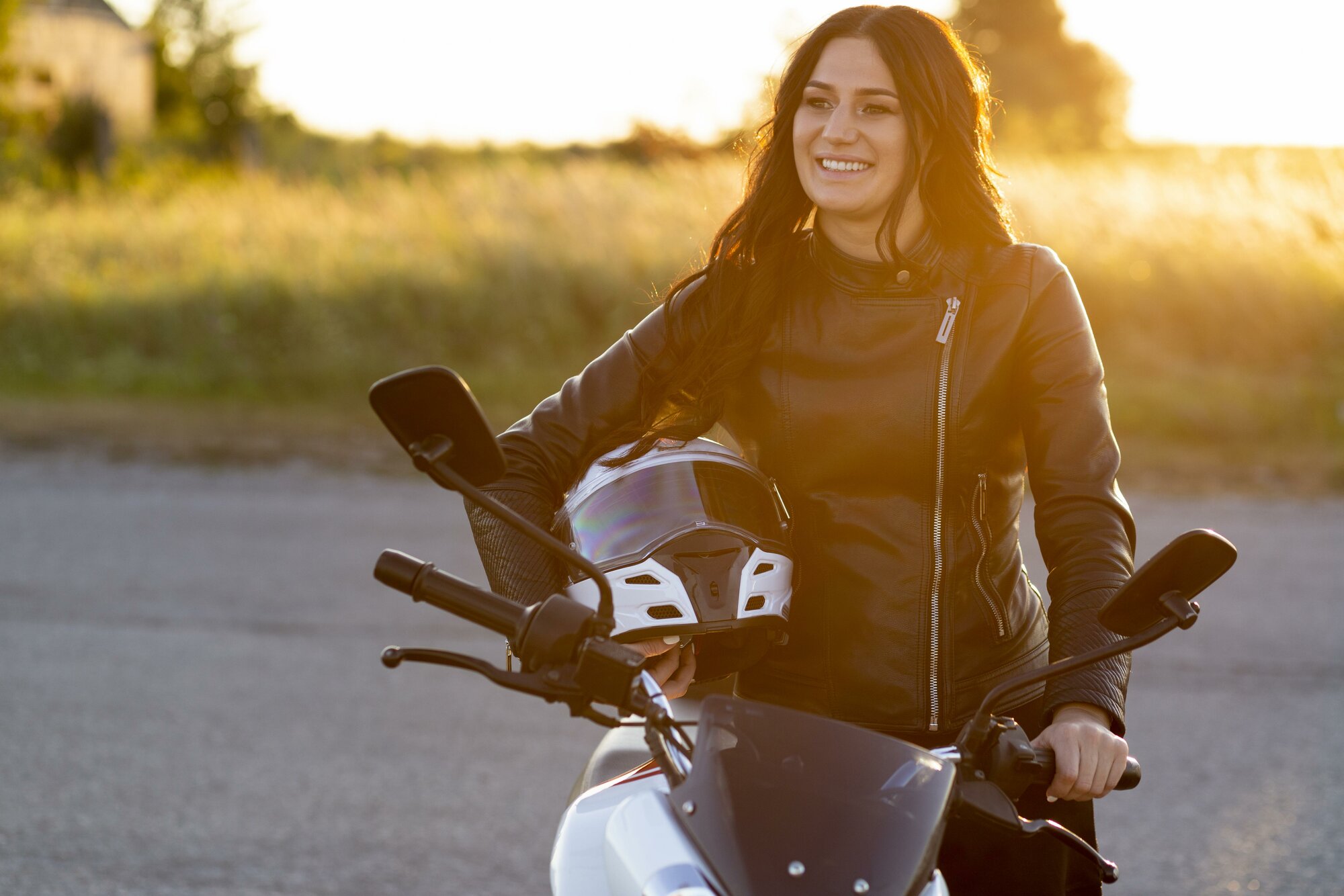 Motorkárka sedí na motorke s prilbou v ruke, ktorá je pre jej bezpečnosť mimoriadne dôležitá