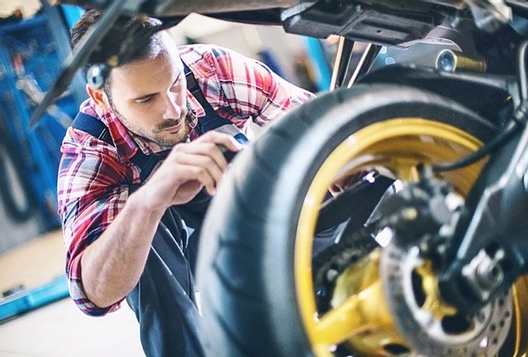 Muž čistí reťaz na motorke.