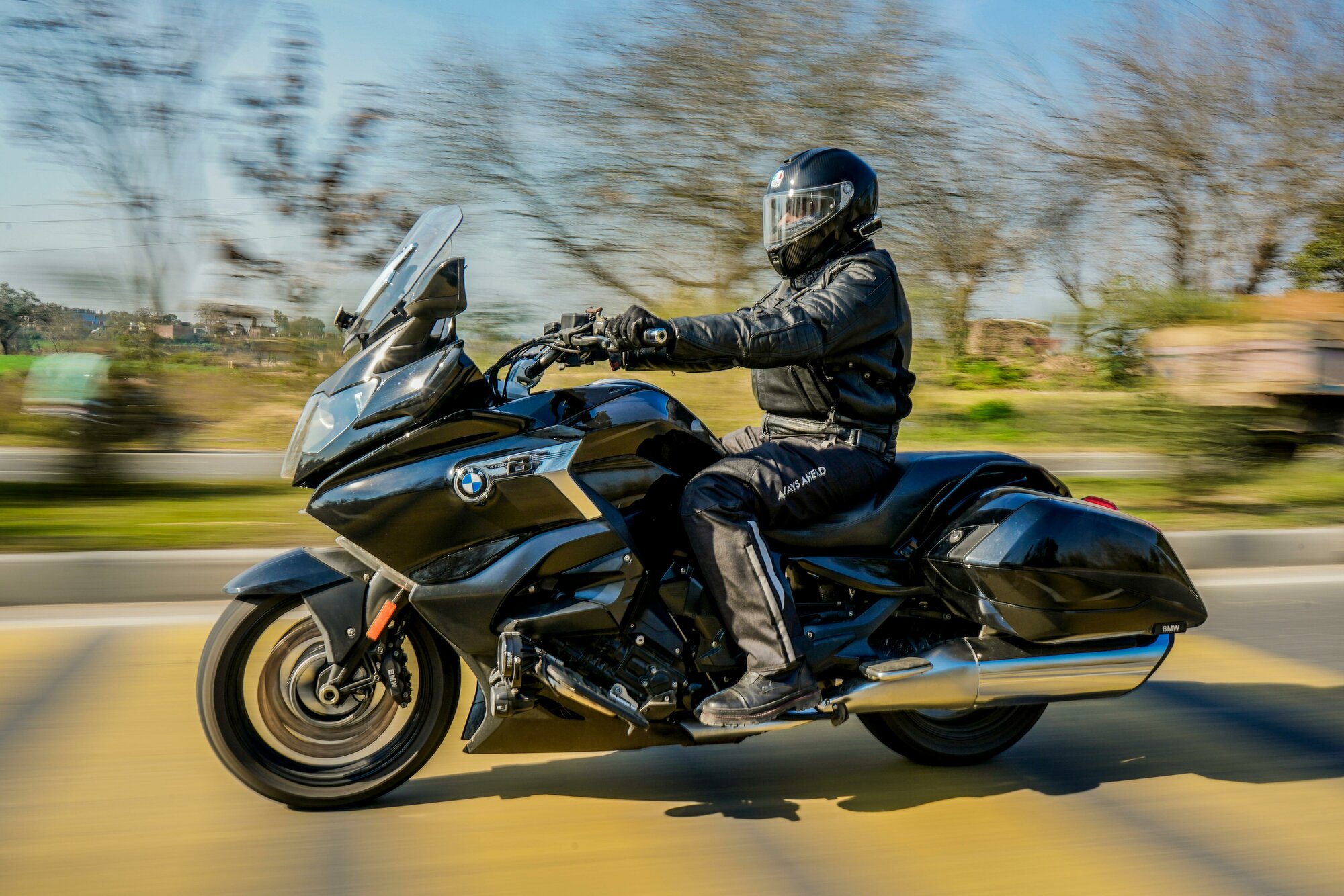 Muž jazd&iacute; na čiernej motorke v čiernej kombin&eacute;ze a prilbe na motorku.